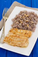 fried fish with boiled buckwheat on white dish