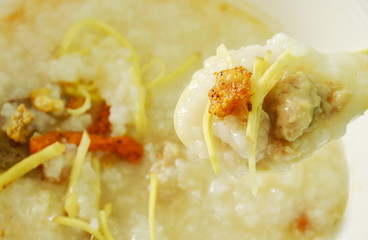 rice congee with minced pork and slice ginger on plastic soup spoon