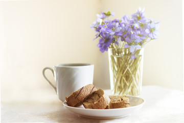 Delicious breakfast - biscuit roll with tea on a background of sunny violets