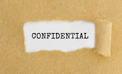 Text Confidential appearing behind ripped brown paper.