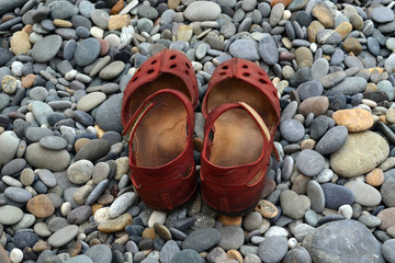 Red sandals on a pebble beach