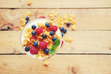 Crunchy corn flakes with some wild berries in a glass cup.