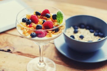 Golden corn flakes, Hercules oat and some berries in a cup on a wooden table.
