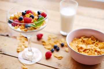 Crunchy corn flakes with some wild berries in a glass cup.