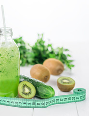 Fresh cucumber, kiwi and cucumber smoothie bottle and measuring.