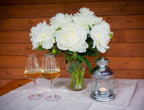 Bouquet of white peonies, glasses of wine and lantern