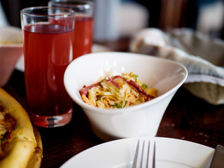Cabbage salad and glass with compote on the table in a cafe