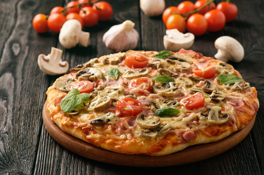 Homemade pizza with ham,mushrooms, tomatoes and cheese.