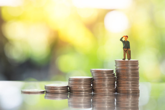 Miniature climbers standing on top stack of coins. Business finance, challenging, compitition concept.
