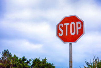 Stop road sign against cloudy sky.