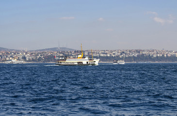 Traditional public ferry crosses Bosphorus from European to Asian side. It's a sunny summer day in Istanbul.