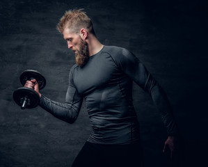 Sporty bearded male holds dumbbell.