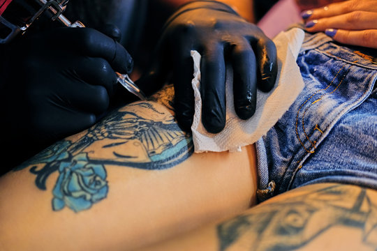 Close up image of making a tattoo on a woman's leg.