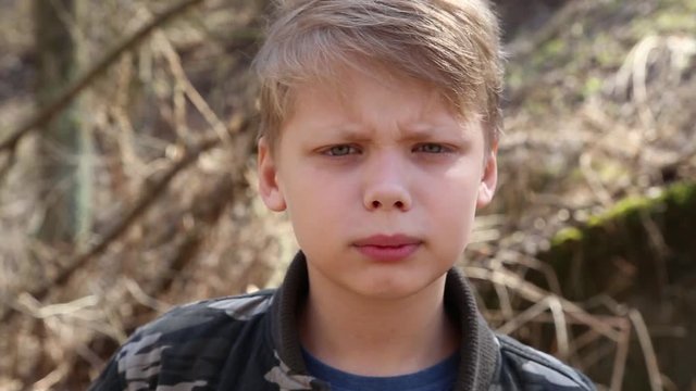 Closeup portrait of funny angry boy. First kid is smiling then makes angry face. Real time full hd video footage.