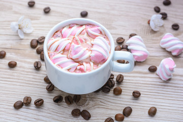 Mug of hot coffee with marshmallows on a wooden background 