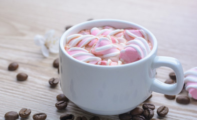 Mug of hot coffee with marshmallows on a wooden background 