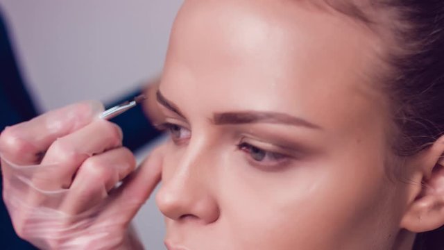 Professional make-up artist drawing eyebrows of model. Beauty, makeup and fashion concept. Close up.