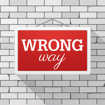 Simple red sign with text 'Wrong Way' hanging on a gray brick wall. Grunge brickwork background, textured rough surface. Creative business interior template for web, shop, store, supermarket.