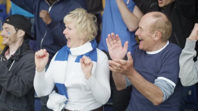  Excited mature couple in sports crowd celebrating & cheering on their team