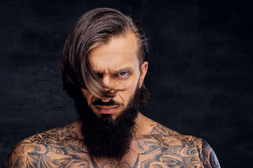 Portrait of tattooed shirtless bearded male.