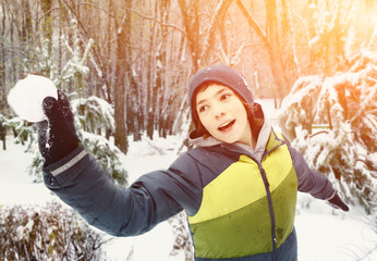 teen boy throwing snow ball outdoor on winter park snowy background