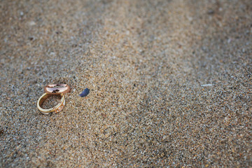 Fototapeta na wymiar Gold and silver wedding rings in sand