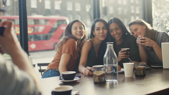  Happy group of female friends pose for photo in city coffee shop