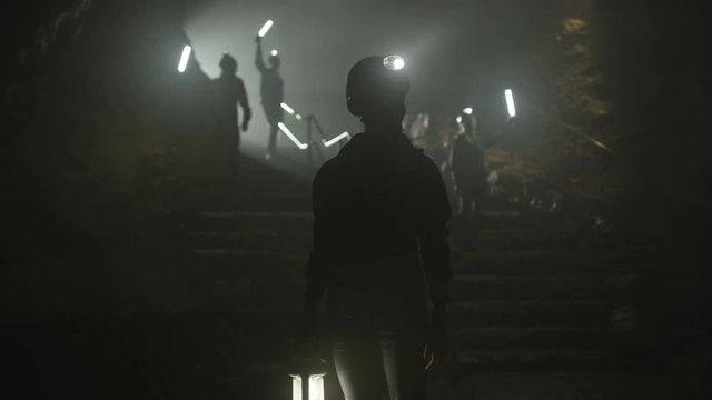  Spelunkers in underground cave, silhouetted in the dark with lamps glowing