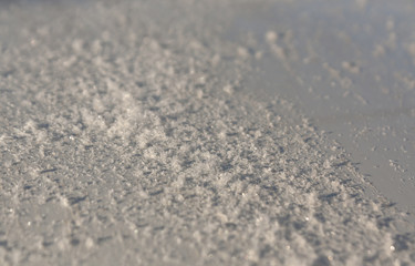 Snow on metal car surface with blur effect.