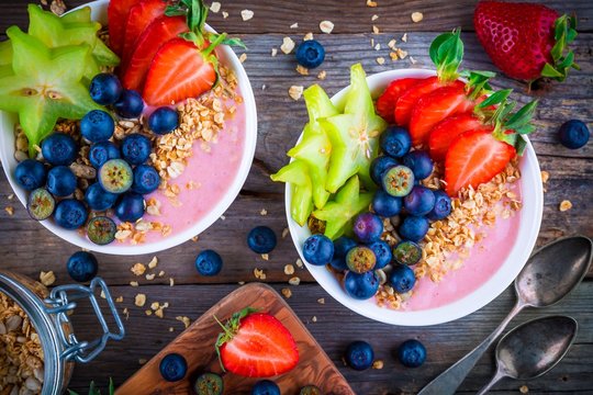 Healthy breakfast bowl: raspberry smoothies with granola, blueberries, strawberries and carambola