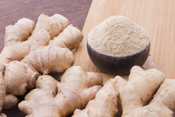 Powdered roots and ginger grated on wooden background