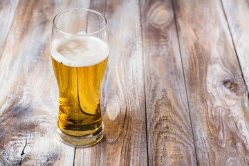 Glass of light beer on wooden background. October fest or football concept. Copy space
