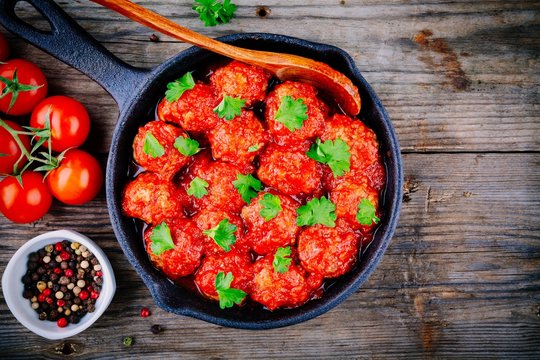Meatballs with tomato sauce and parsley in cast iron pan