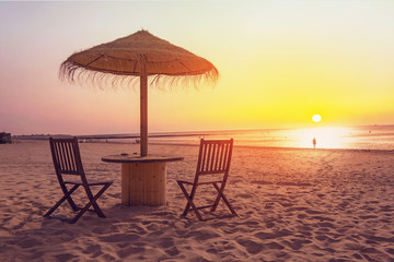 Wooden table and chairs with umbrella on the beach 