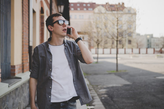 Young hipster man walking on the street and talking on phone