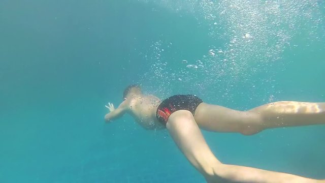 happy child swims with enjoyment under the water in the pool