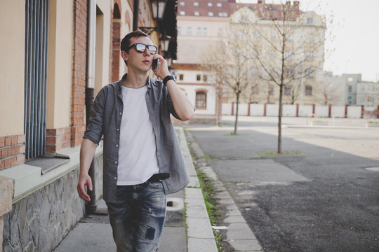Young hipster man walking on the street and talking on phone