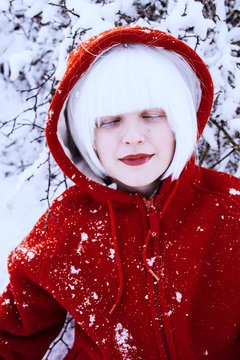 Retrato artístico invernal de una chica con el pelo blanco y una sudadera roja en la nieve 