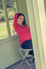 Pregnant woman wearing red shirt posing in garden pergola.