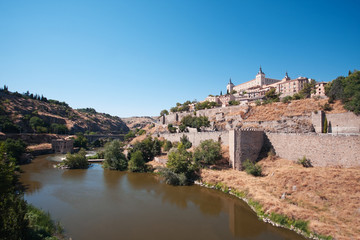 Fototapeta na wymiar Old Toledo on the bank of the river Tajo. Blue sky. Sunny weather 
