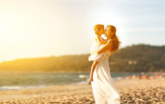 happy family at beach. mother hugging baby daughter at sunset