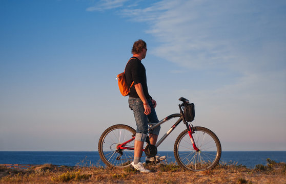 A cyclist on a sunset background by the sea. Bicycle tour along the seashore. Evening bike tour. Bright sunset against the background of the Mediterranean Sea
