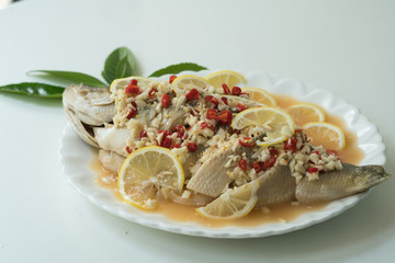 A Seabass steam with lemon, garlic and red chili - Thai food, on white plate