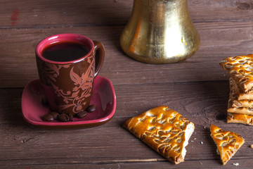 Cup of cofee, tirk and cookies on old wooden table opposite sackcloth background