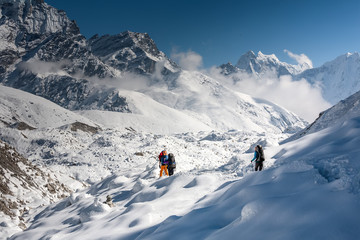Fototapeta na wymiar Trekkers crossing Gokyo glacier in Khumbu valley on a way to Everest Base camp