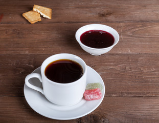 Cup of tea with jam, biscuits and marmalade on old wooden table against the background of burlap. Selective focus. Shallow depth of field