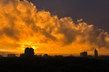 Fototapeta premium Urban sunset skyline with dramatic orange clouds.