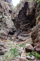 Fototapeta na wymiar Huge brown rocks of the Masca Gorge. Hiking trail passing through the giant cliffs. Tenerife, Canaries, Spain