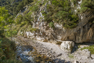 The Rio Cares mountain stream flows through a valley in the foothills of the Picos de Europa National Park. The foothills are also a popular hiking destination and lead along the Camino de Santiago.