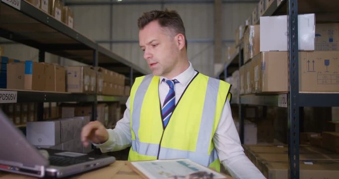  Business manager in industrial warehouse working on laptop computer
